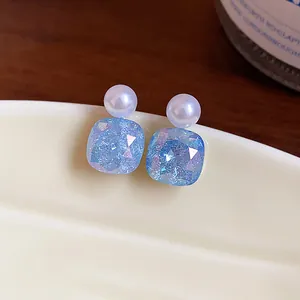 Close-up view of elegant square blue glass stud earrings featuring small white pearls