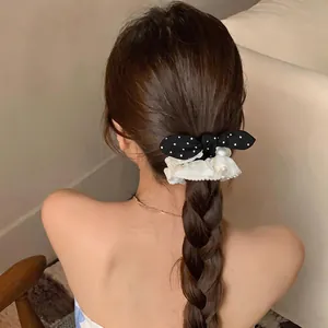 Detail showing a polka dot bow scrunchie with pearls and lace on a braided hairstyle