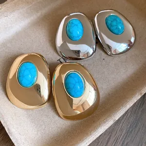 Close-up of vintage oval stud earrings with turquoise stones in gold and silver finish