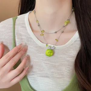 Close-up of green apple pendant necklace with clear beads on a mori style model
