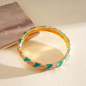 Vista detallada de la incrustación de esmalte de colores en un brazalete dorado con bisagra