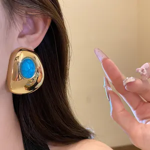 Close-up of vintage gold-tone oval stud earring with turquoise resin center
