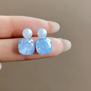 Detailed macro view of elegant blue faceted crystal and pearl earrings with silver posts.
