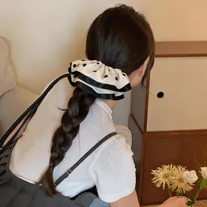 Back view of woman with braided hair wearing a white polka dot fabric scrunchie accessory