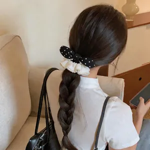 Detailed view of a sweet polka dot bow hair tie with pearl lace on a braided hairstyle