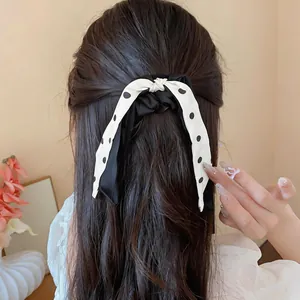 Detailed view of a sweet black and white polka dot ribbon bow hair scrunchie worn on hair