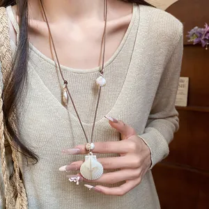 Detail view of a vacation-style shell and starfish pendant necklace on a model