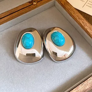 Close-up detail of vintage silver-tone oval stud earrings with turquoise resin stone inlay