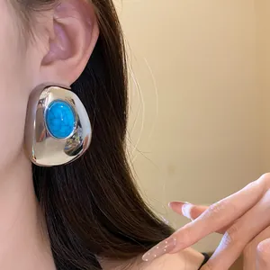Close-up of a vintage silver-tone stud earring with a blue oval resin stone.