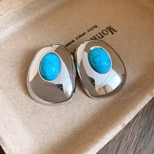 Close-up of vintage silver earrings with turquoise-colored resin inlays on a tray.