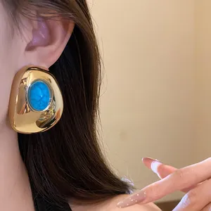 Close-up shot of a vintage style gold oval earring featuring a vibrant turquoise stone inlay