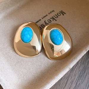 Close-up detail of vintage gold-plated oval stud earrings with blue turquoise-style resin stones