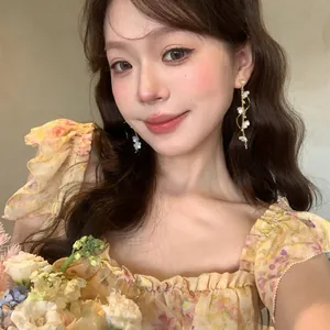 Elegant long floral tassel earrings with shimmering crystals worn by an Asian model
