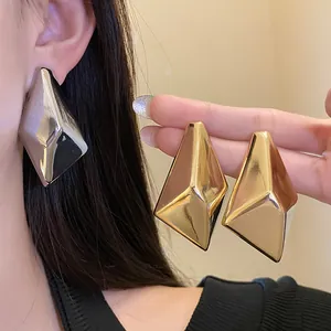 Detailaufnahme von geometrischen Ohrsteckern mit Gold- und Silber-Metallfinish