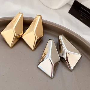 Detailaufnahme von geometrischen unregelmäßigen Metall-Ohrsteckern in Gold und Silber