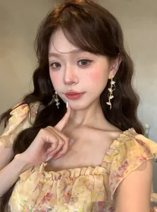 Close-up of elegant long flower tassel earrings with rhinestones worn by a model
