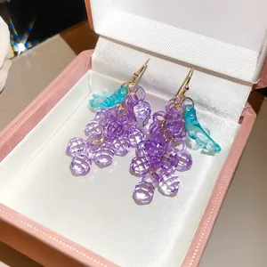 Vue détaillée de boucles d'oreilles en grappe de raisin violettes dans leur boîte