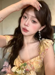 Model wearing sparkling floral tassel earrings with elegant blue flower accents.