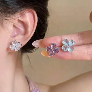 Close-up of sparkling flower stud earrings in white, purple, and blue zircon gems