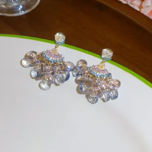 Gros plan de boucles d'oreilles pompons en zircon en forme d'éventail avec perles bleues.