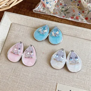 Close-up of zircon teardrop earrings in blue, pink, and white oil drip finishes.