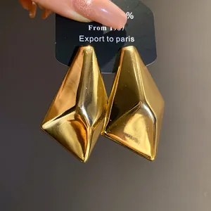 Makroaufnahme von geometrischen unregelmäßigen Goldohrringen mit glänzendem Spiegel-Finish