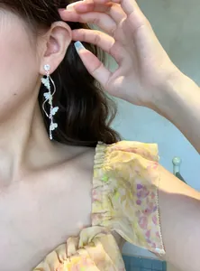 Close-up of sparkling diamond flower long tassel earrings on model
