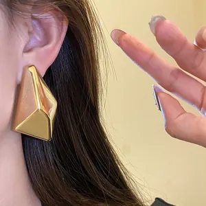 Detailaufnahme eines minimalistischen goldenen geometrischen Ohrsteckers am Ohr