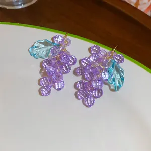 Vue détaillée de boucles d'oreilles raisin avec perles violettes et feuilles bleues.