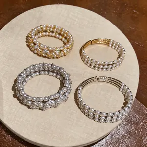 Elegante bracciale rigido multistrato con perle e strass, finiture oro e argento.