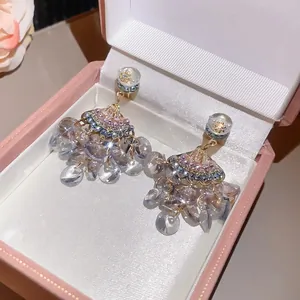 Détail macro de boucles d'oreilles en zircon en éventail avec perles violettes en coffret