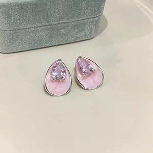 Close-up of pink pear-shaped zircon stud earrings with enamel finish and silver needles