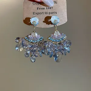 Gros plan sur des boucles d'oreilles en forme d'éventail avec glands en cristal