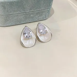 Elegant pear-shaped zircon stud earrings with white enamel finish on a neutral background.
