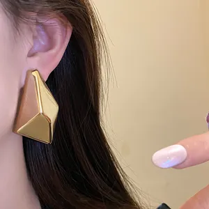 Detailaufnahme unregelmäßiger geometrischer Goldohrstecker mit glänzendem Finish