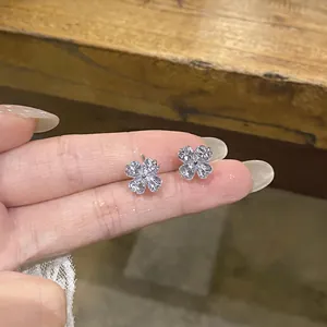 Close-up detail of silver-toned four-leaf clover stud earrings featuring sparkling cubic zirconia stones