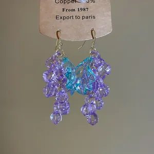 Vue détaillée des boucles d'oreilles grappe de raisin violettes avec une feuille bleue