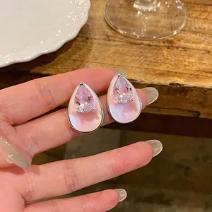 Close-up detail of pink enamel teardrop stud earrings with clear zircon on hand