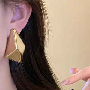 Detailaufnahme von klobigen unregelmäßigen geometrischen Goldsteckern mit glattem Spiegelglanz
