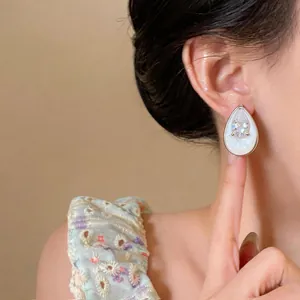 Close-up of elegant tear-drop zircon stud earring on female model's ear