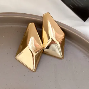 Detaillierte Nahaufnahme goldener unregelmäßiger geometrischer Ohrstecker mit Metallglanz