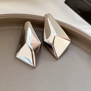 Nahaufnahme von silbernen geometrischen Ohrsteckern mit glänzender Metalloberfläche.