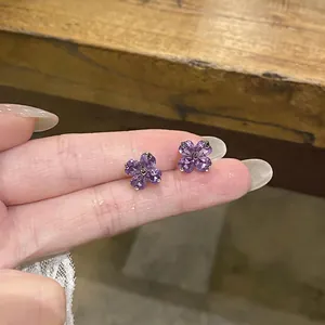 Macro view of purple flower stud earrings featuring sparkling heart-shaped zircon petals