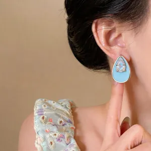 Detailed view of a light blue enamel waterdrop earring with a sparkling zircon center