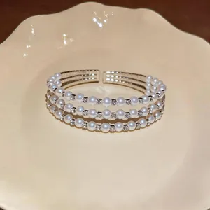 Dettaglio ravvicinato di un elegante bracciale rigido a tre strati con perle bianche e strass