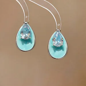 Close-up of elegant waterdrop earrings with mint enamel and pear-cut zircon