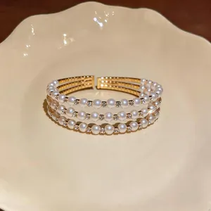 Vista dettagliata di un elegante bracciale rigido a tre strati con perle e cristalli