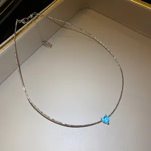 Macro view of a blue heart-shaped pendant on a textured silver-toned clavicle chain
