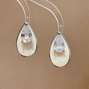 Close-up of teardrop stud earrings with pear-shaped zircon and cream enamel inlay.