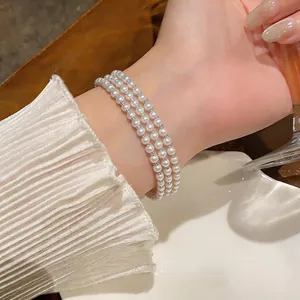 Macro dell'elegante bracciale di perle multistrato con delicati strass indossato al polso.